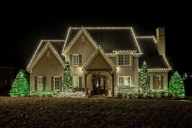 Large Connecticut colonial home with soft white Christmas roofline lighting at dusk